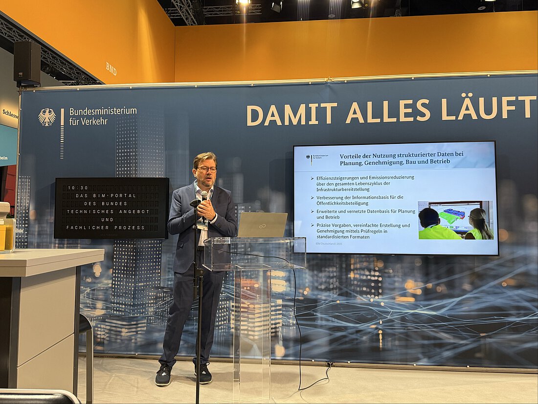 Am Stand von BIM Deutschland wird eine Power Präsentation gezeigt. Sie wird von einem Mann moderiert.