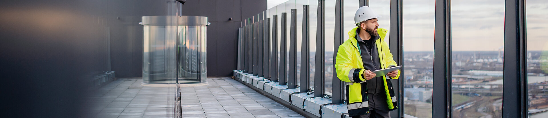 Ein Ingenieur schaut von dem Balkon eines modernen Gebäudes über eine Stadt.