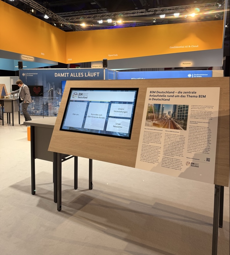 Eine Messestand vom BIM Deutschland, bestehend unter anderem aus einer Infotafelnund einem großen Touchscreen zur interaktiven Information.