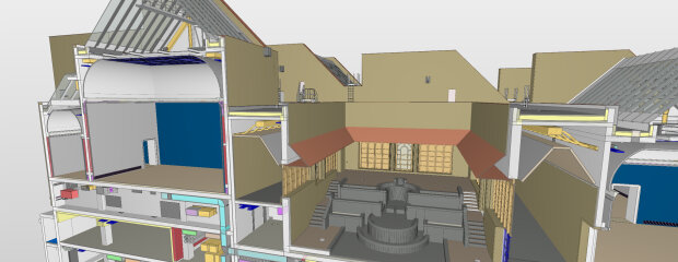 Digitale Gebäudemodellierung eines mehrstöckigen Gebäudes im BIM-Modell, dargestellt im Schnitt: sichtbar sind Dachkonstruktionen, technische Einbauten, Wand- und Deckenschichten sowie ein zentraler Innenraum mit Treppenanlage und Brunnen.